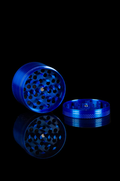 Blue cannabis grinder disassembled on a reflective black surface.