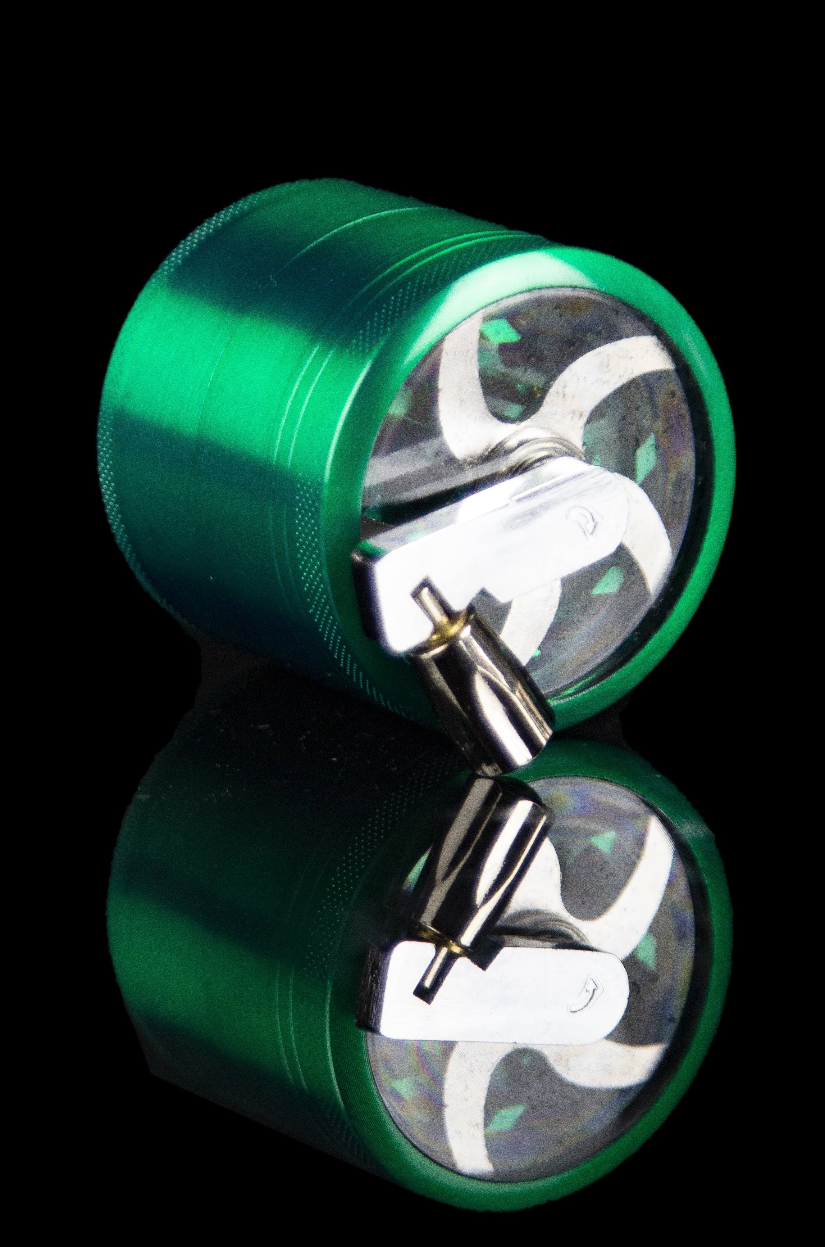 Green metal cannabis grinder, disassembled to show inner grinding components.