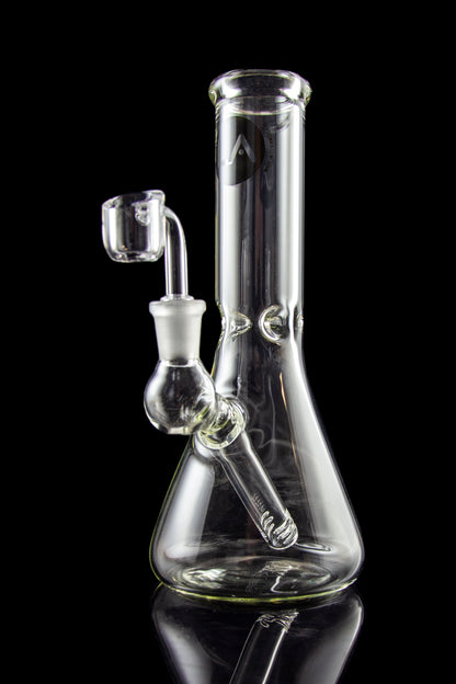 Clear glass water pipe (bong) with a quartz banger, studio shot on a black reflective surface.