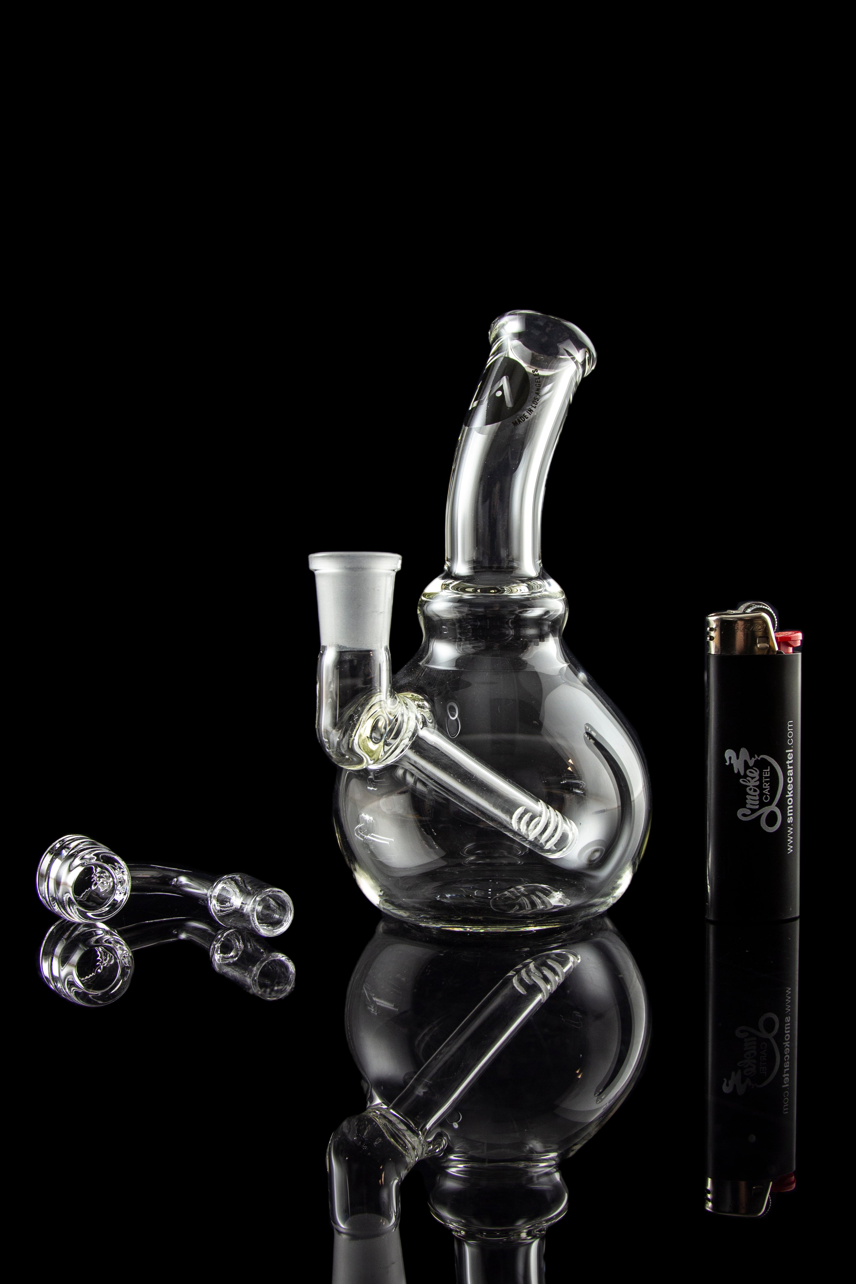 A studio shot of the LA Pipes Mini Bubble Base Concentrate Rig, reflecting on a dark surface with a sleek, modern aesthetic.