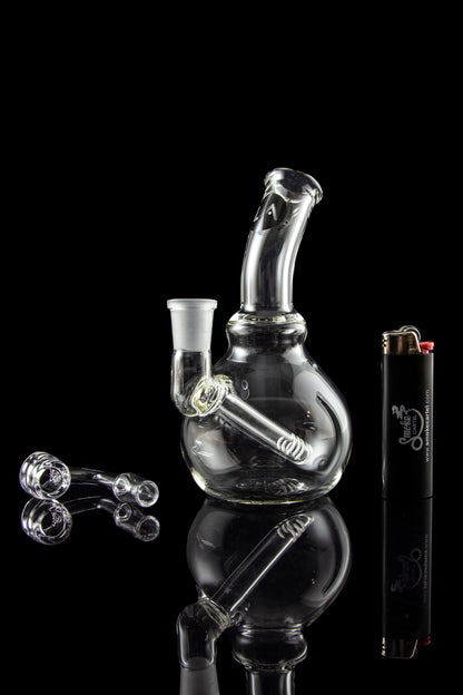 A studio shot of the LA Pipes Mini Bubble Base Concentrate Rig, reflecting on a dark surface with a sleek, modern aesthetic.