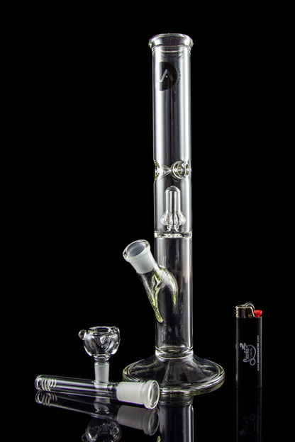 Glass bong with accessories on a reflective surface.
