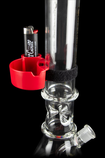 A glass bong with a red silicone attachment holding a lighter, showcasing intricate glasswork and a water chamber.
