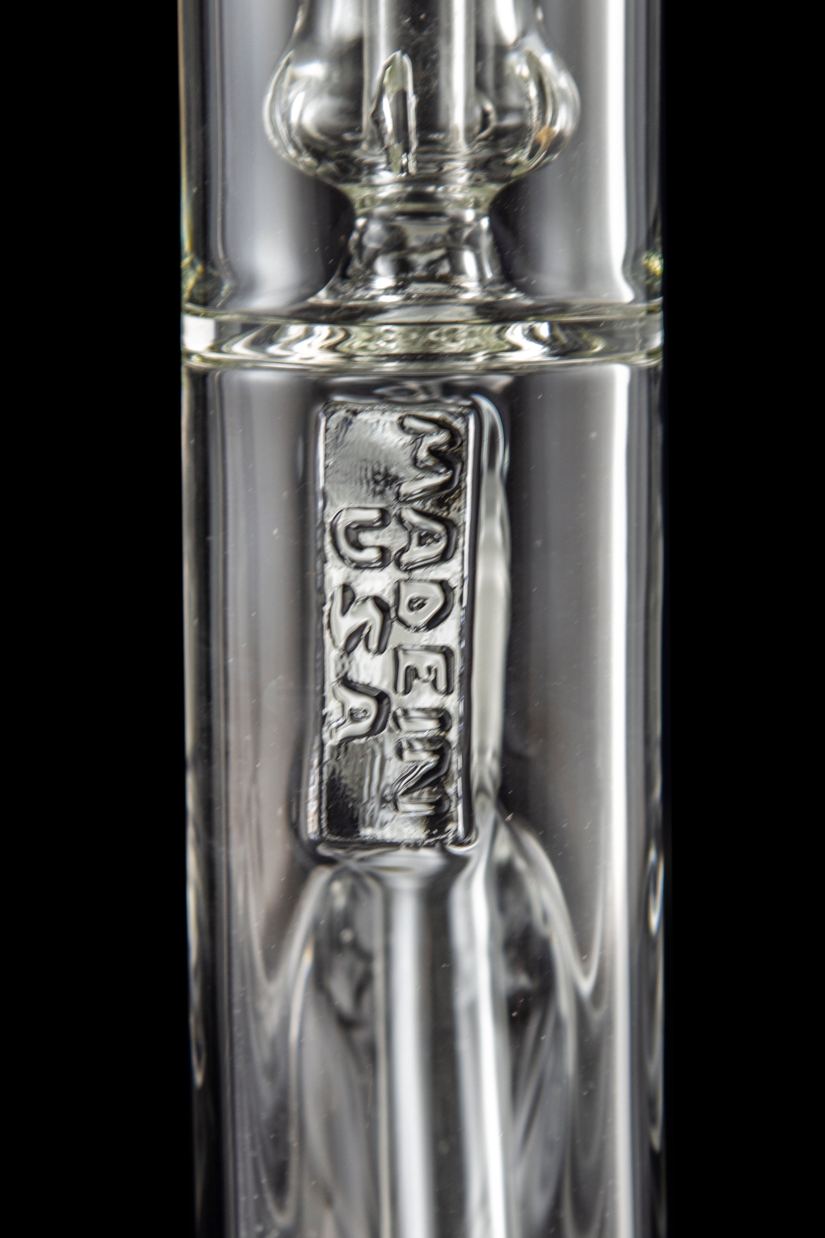 Close-up of a clear glass bong with etched branding.