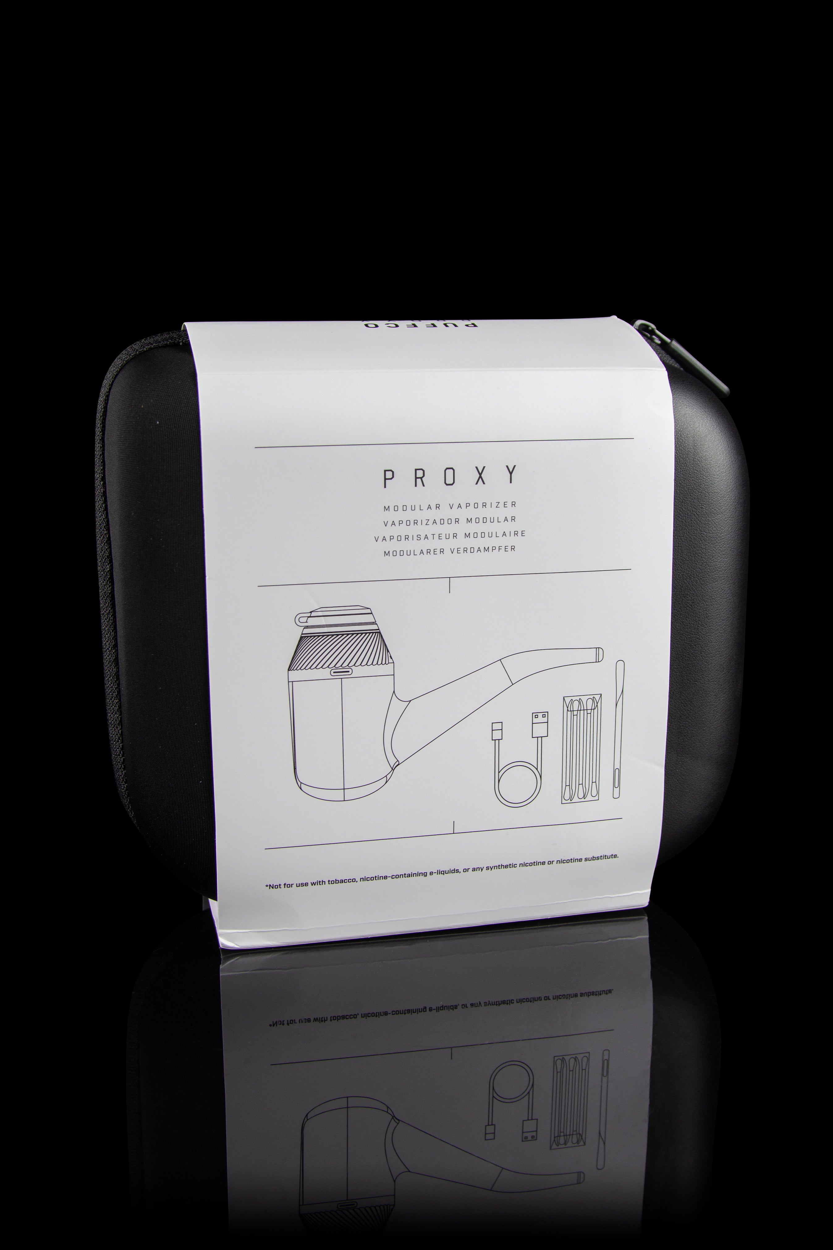 Closed black case for a “PROXY” modular vaporizer with line-drawing diagrams of components and a disclaimer against use with nicotine products, reflected on a glossy surface.