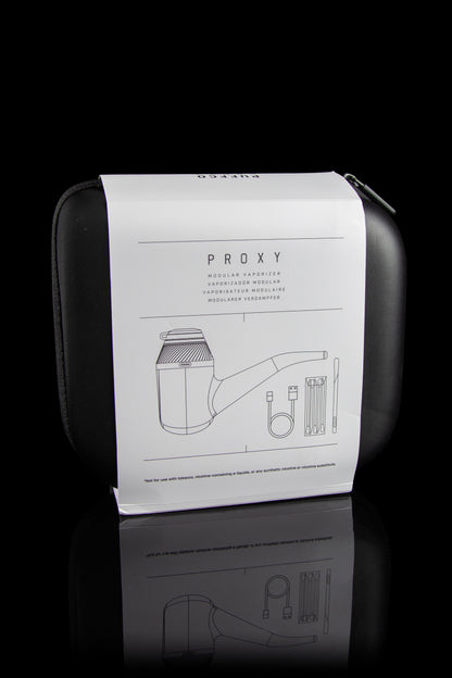 Closed black case for a “PROXY” modular vaporizer with line-drawing diagrams of components and a disclaimer against use with nicotine products, reflected on a glossy surface.