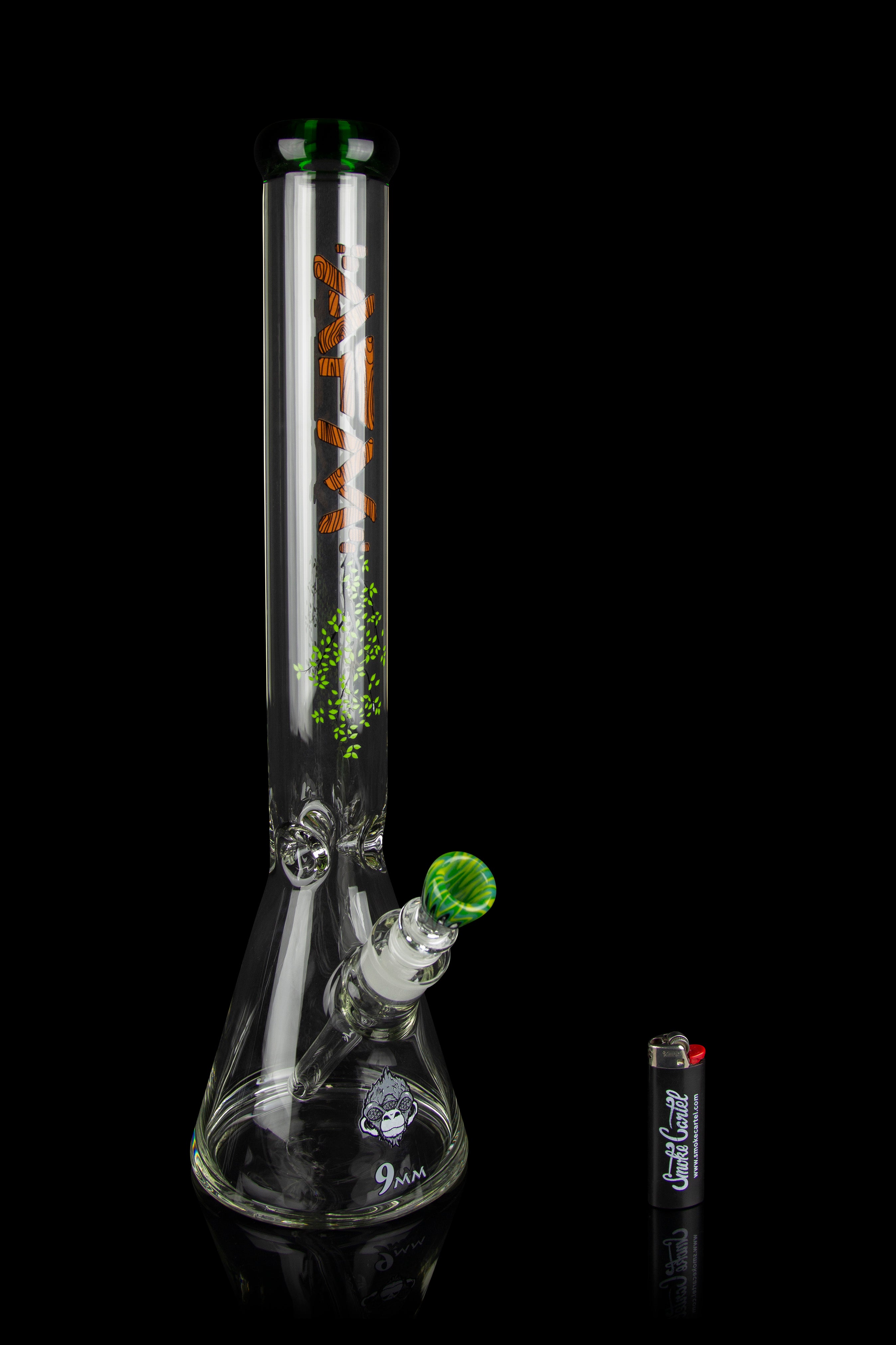 A clear glass water pipe (bong) with green accents and a 9mm downstem, positioned next to a container of rolling papers.