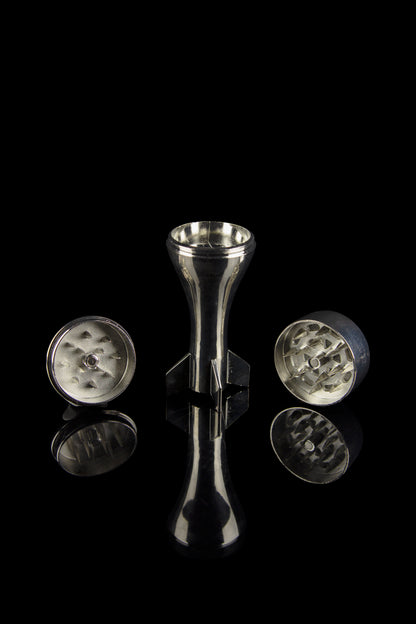 Silver cannabis grinder disassembled on a reflective black surface.