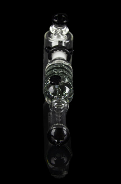 Clear glass bubbler water pipe with skull-shaped chambers, isolated on black.