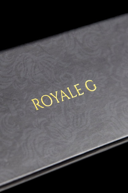 Close-up of a black box with gold foil lettering that reads "ROYALE G", suggesting luxury cannabis packaging.