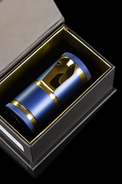 Blue and gold cannabis grinder presented in an open black box.