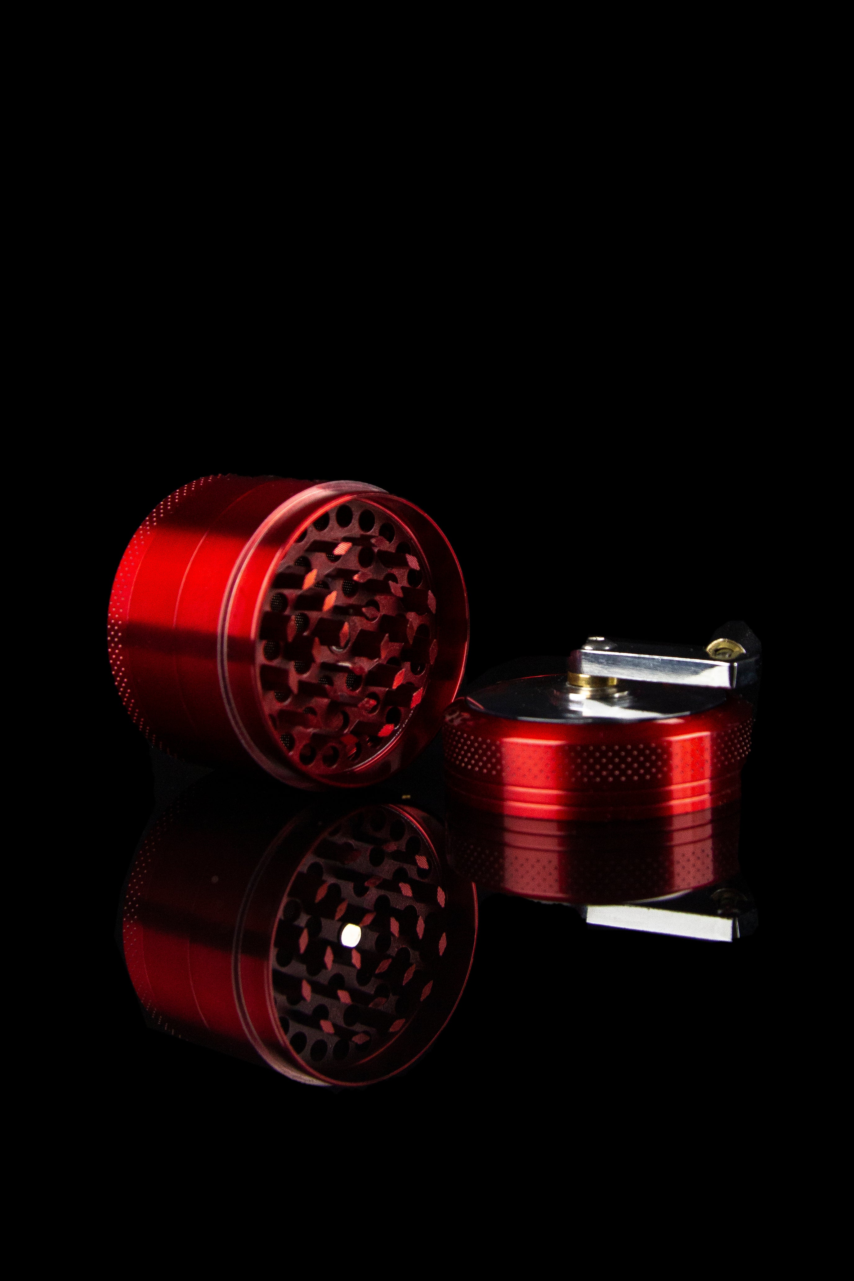 Red cannabis grinder and lighter on black background.