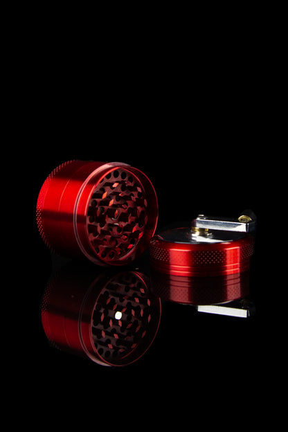 Red cannabis grinder and lighter on black background.