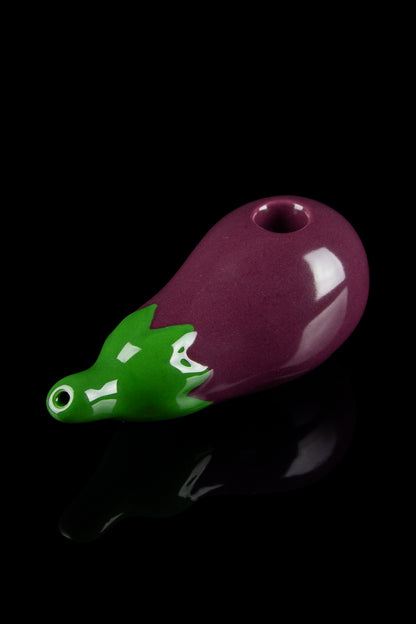 Glass pipe shaped like an eggplant with alligator head detail, isolated on black.