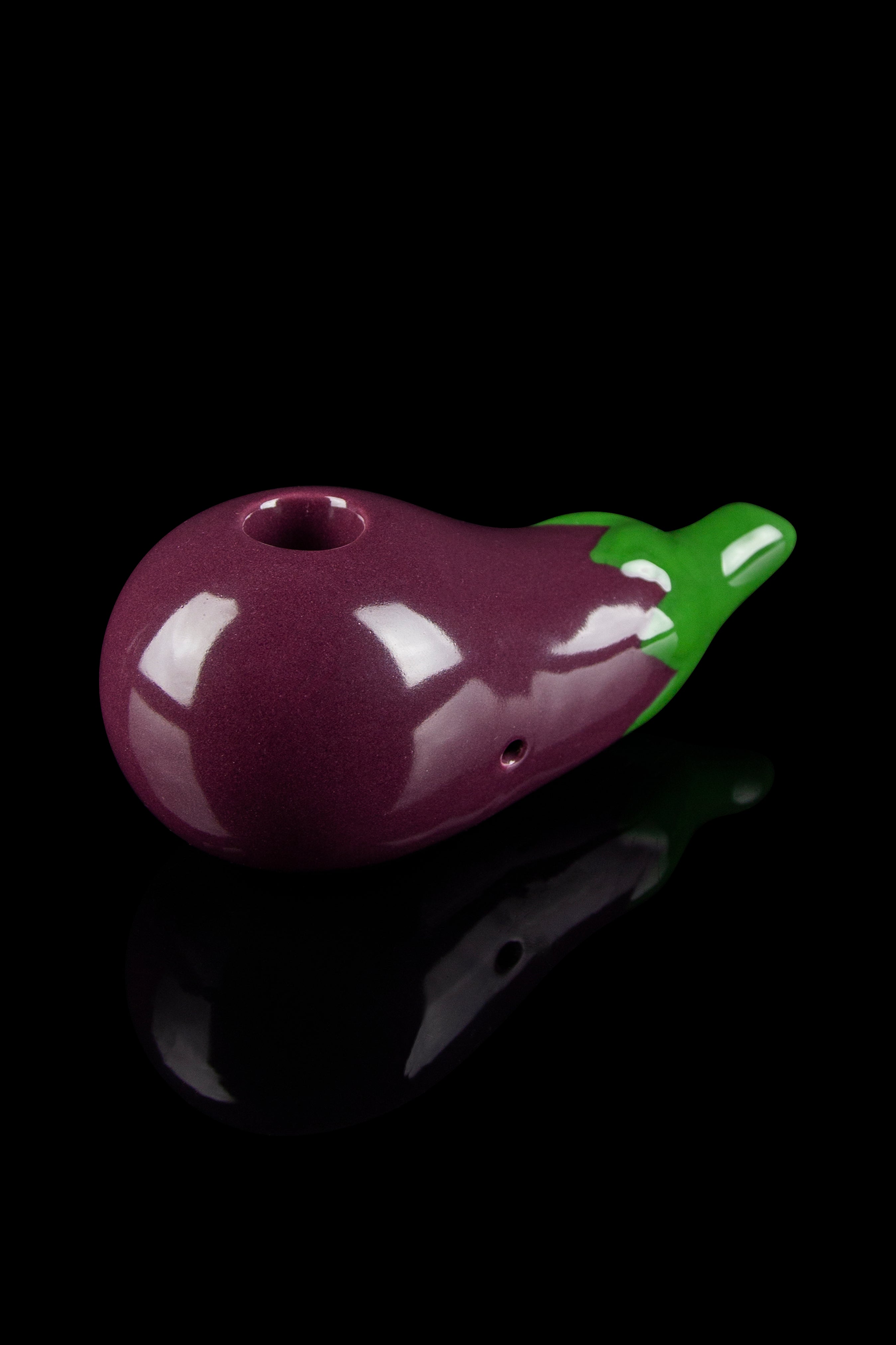 Purple glass pipe shaped like an eggplant against a black background.