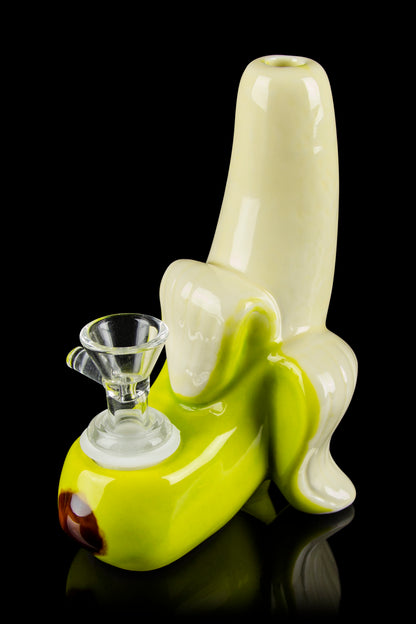 A glass banana-shaped water pipe with a clear glass bowl rests on a reflective black surface.