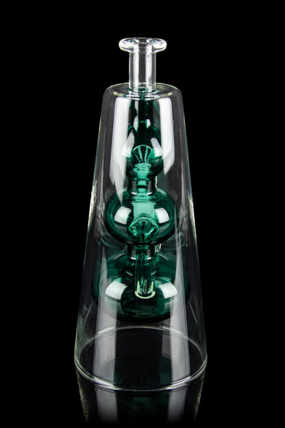 Emerald green glass rig encased within a clear glass enclosure, reflecting on a dark surface.