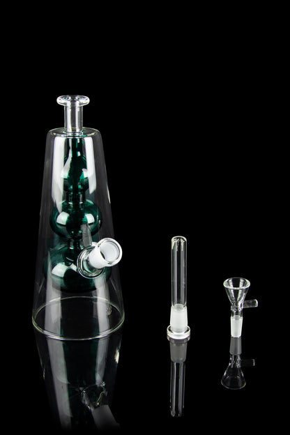 A glass water pipe (bong) with green accents, alongside two glass inserts, isolated on a black background.