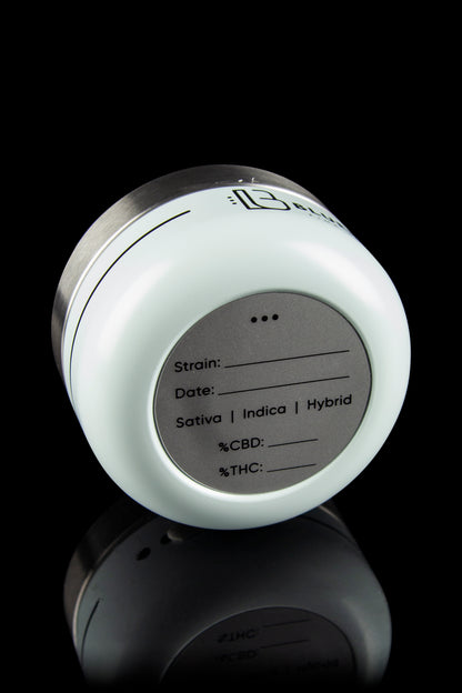 White cannabis storage jar with fill-in fields for strain, date, and THC/CBD percentages, reflecting on a dark surface.