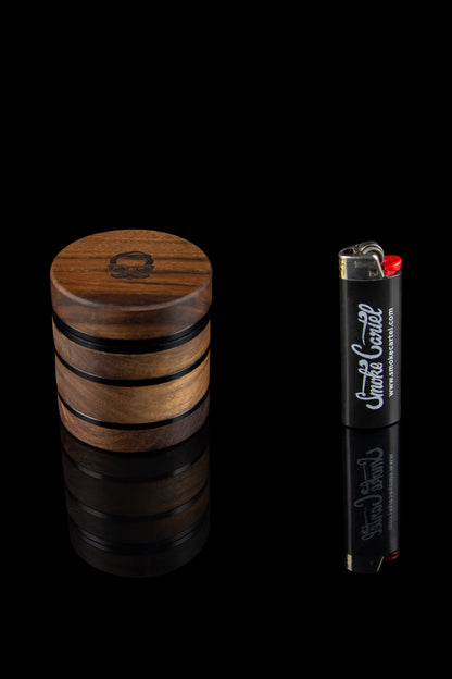 Wooden grinder and lighter with cannabis-related branding against a black background.