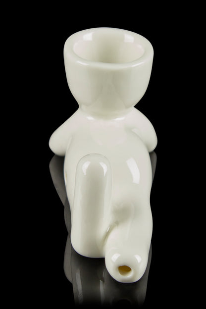 Glass bubbler shaped like a figurine with a mouthpiece and water chamber, reflecting on a black surface.