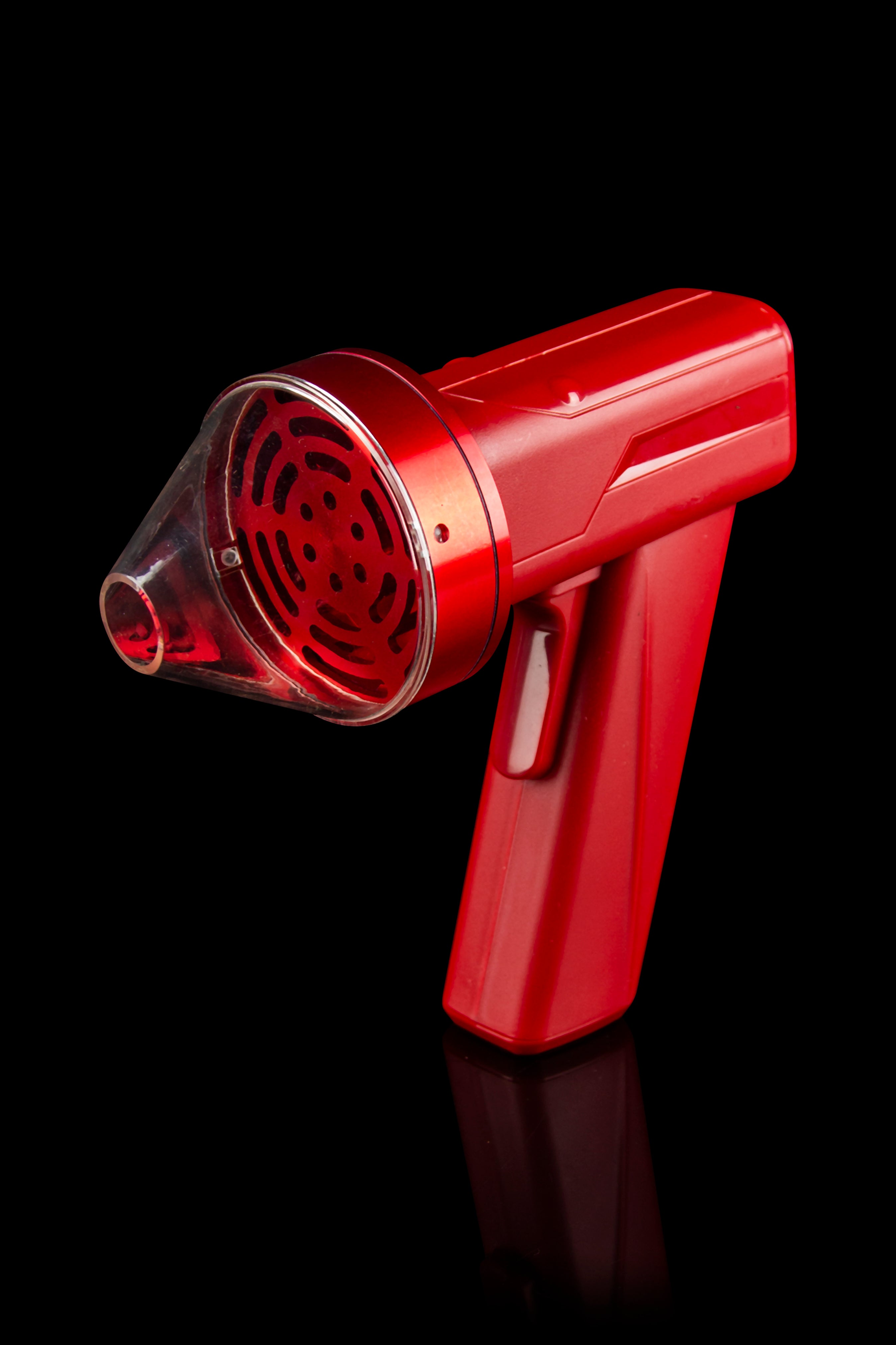 Red cannabis grinder with a clear collection chamber, isolated on black.