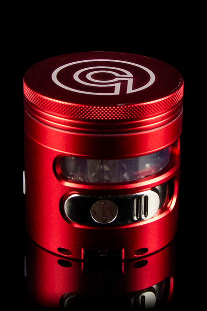 Red cannabis grinder with a clear viewing window, showcasing a metallic interior.