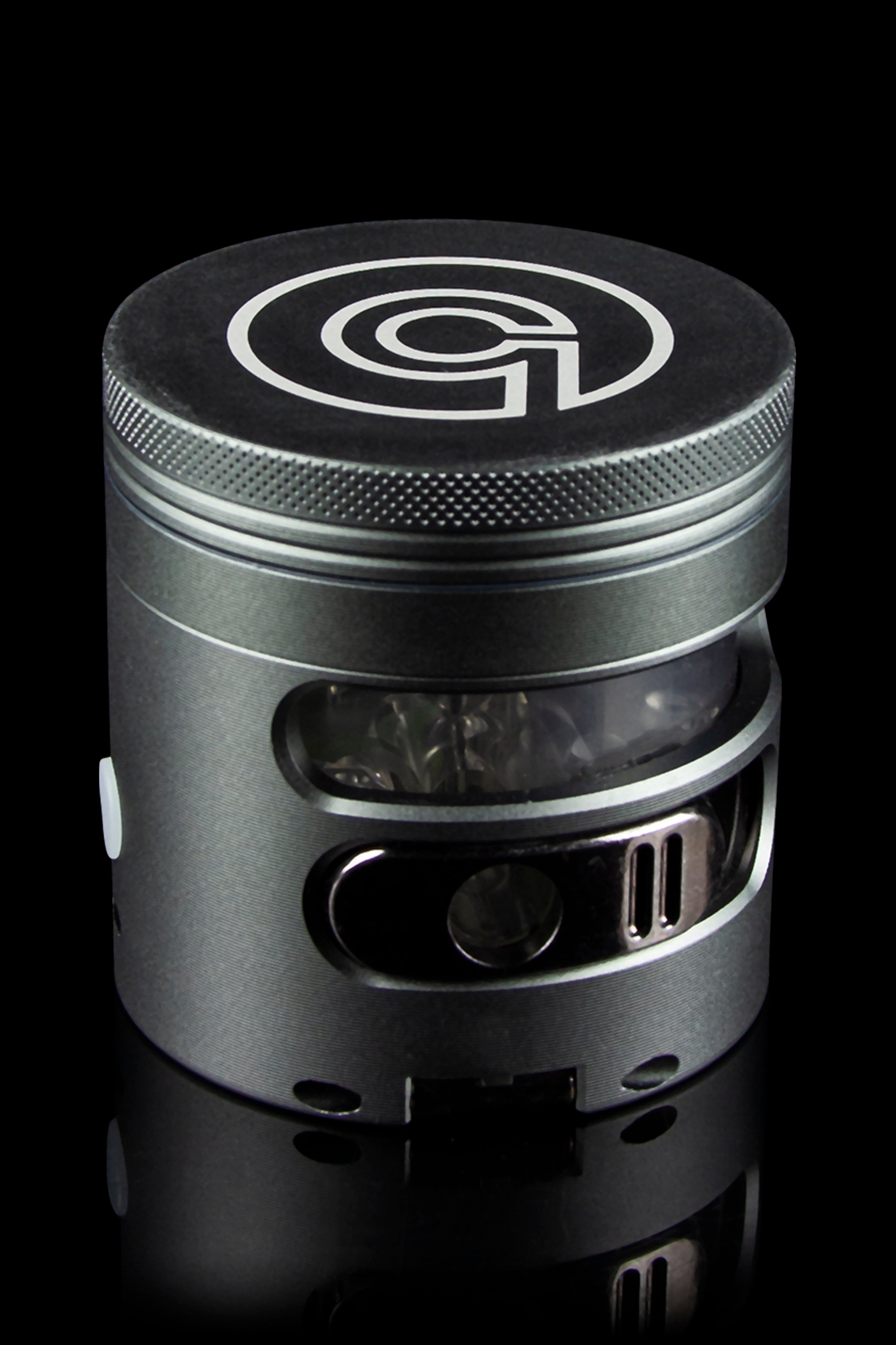 Silver cannabis grinder with a branded top and clear chamber, isolated on a black background.