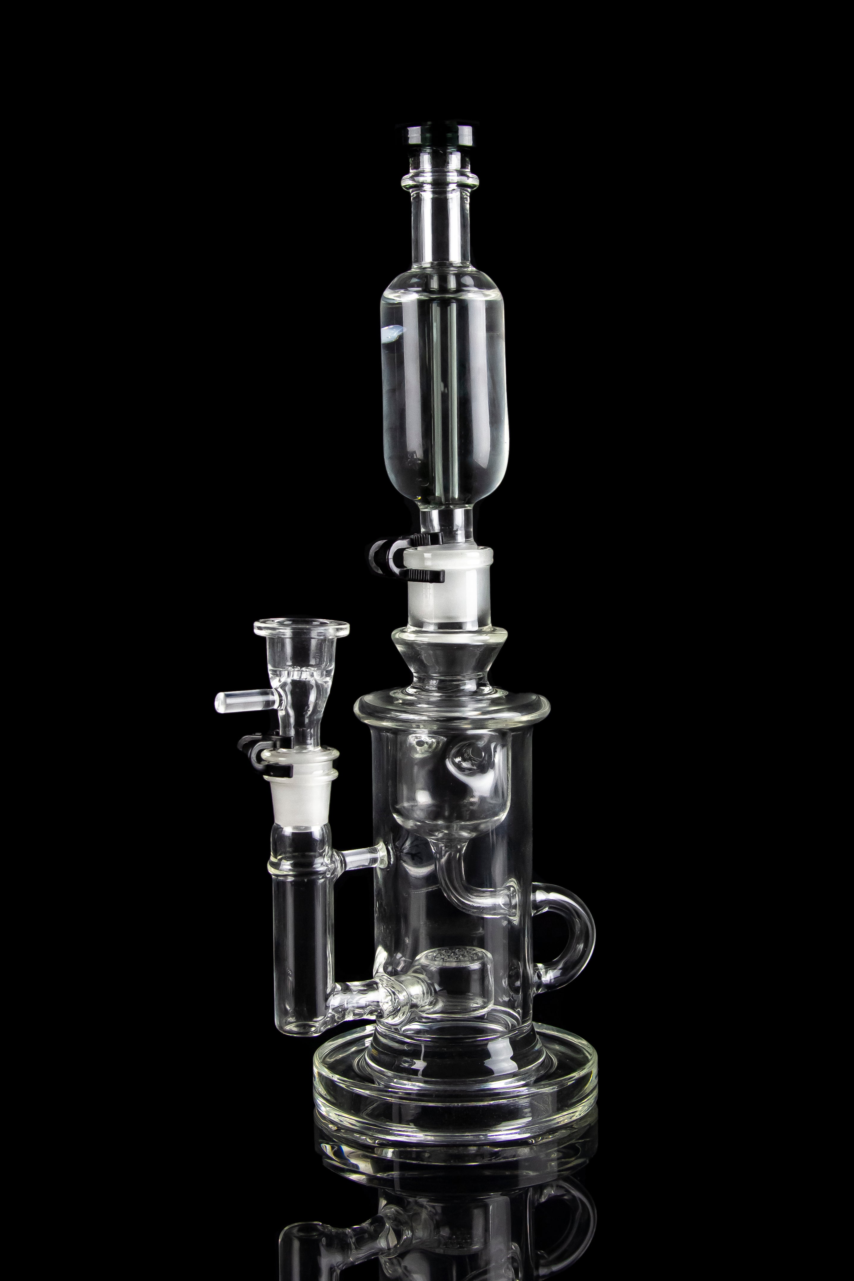 Clear glass water pipe (rig) with multiple chambers and attachments, isolated on a black background.