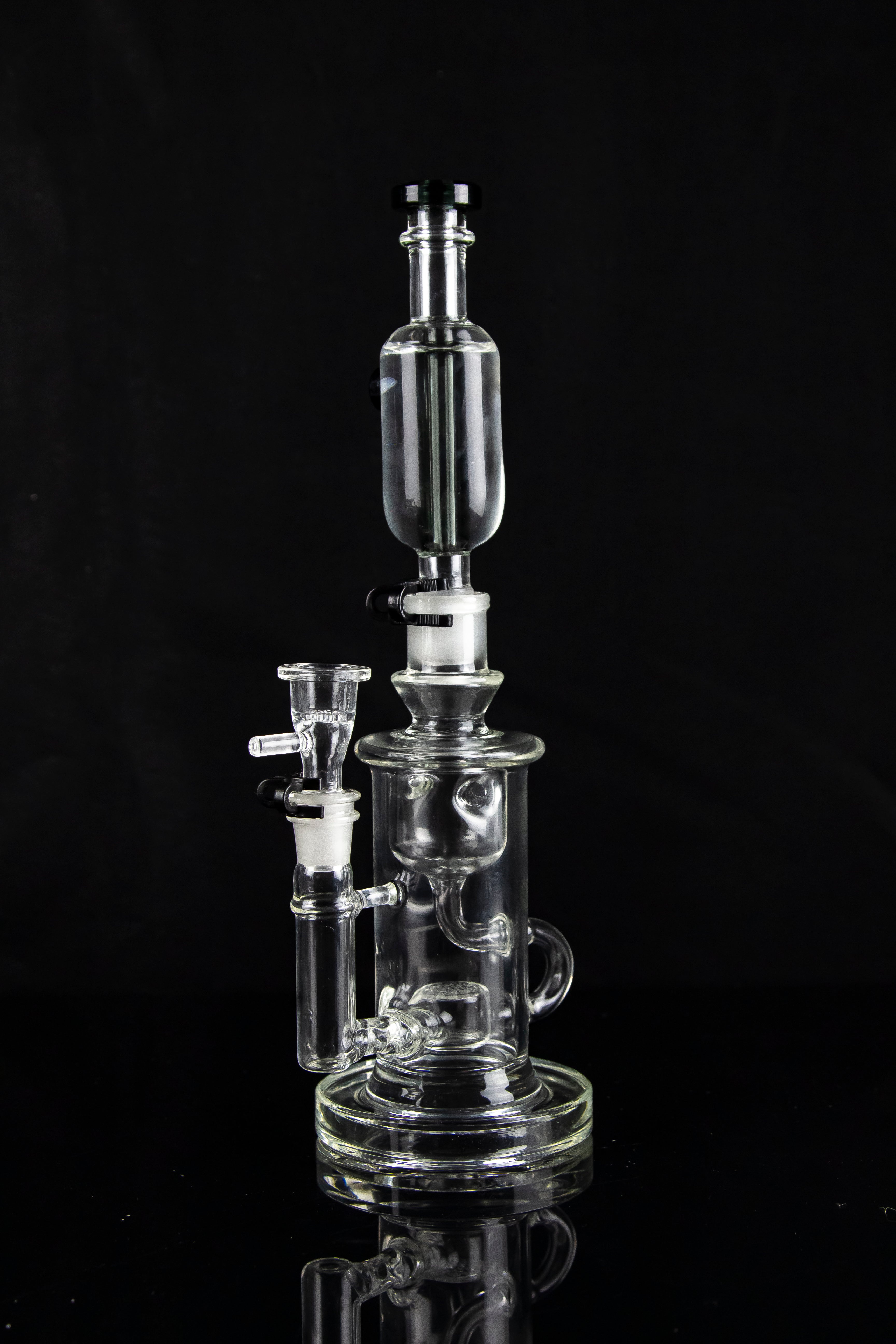 Clear glass water pipe (rig) with multiple chambers and a glass bowl, isolated on black.