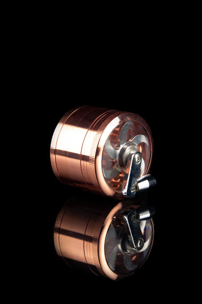 Copper and clear cannabis grinder with reflection on black background.