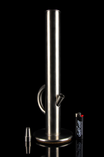 Sleek, silver glass bong with a clear tube and circular mouthpiece, reflecting on a dark surface.