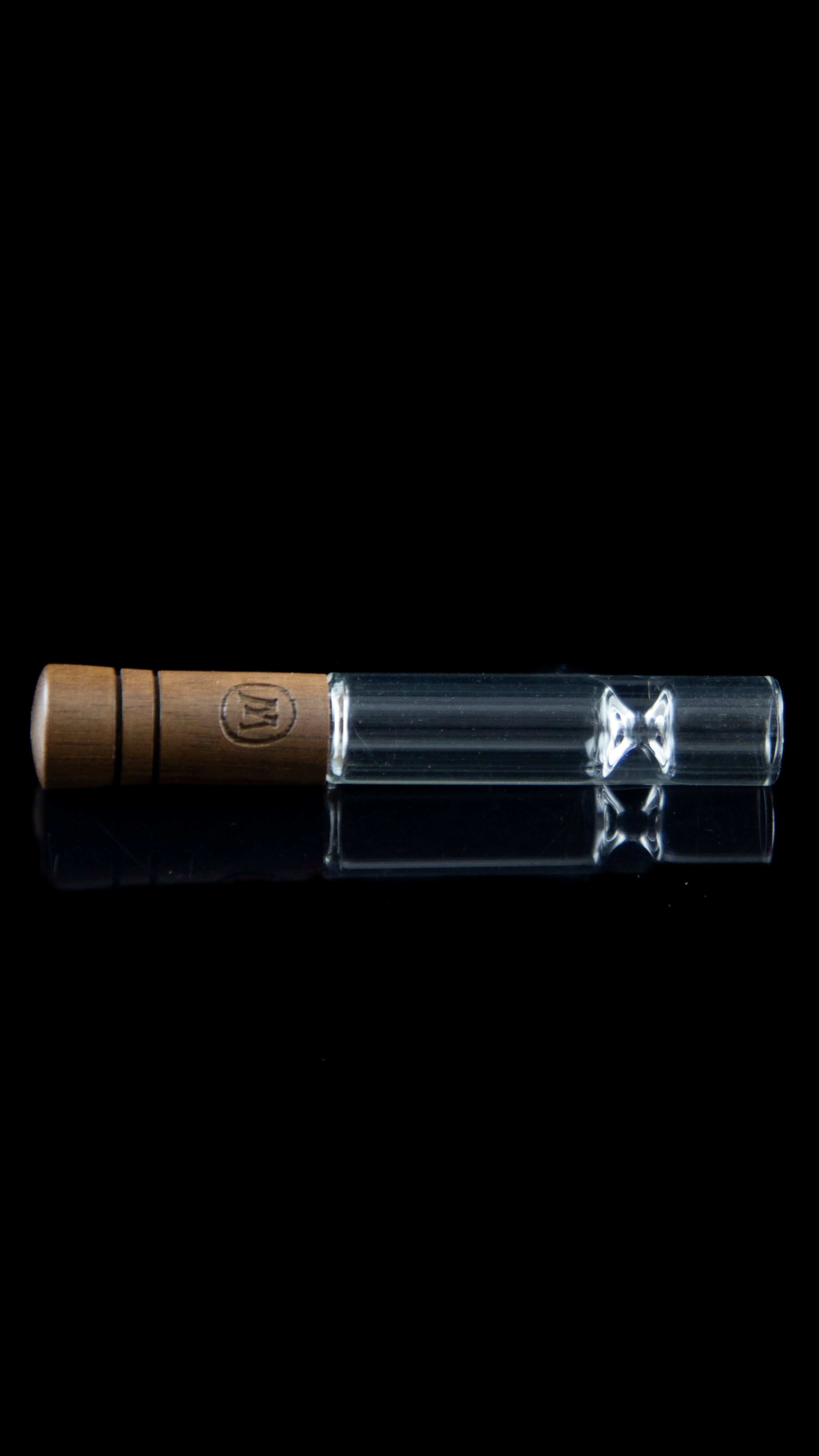 Wooden-tipped glass chillum with visible flower inside, against a black background.