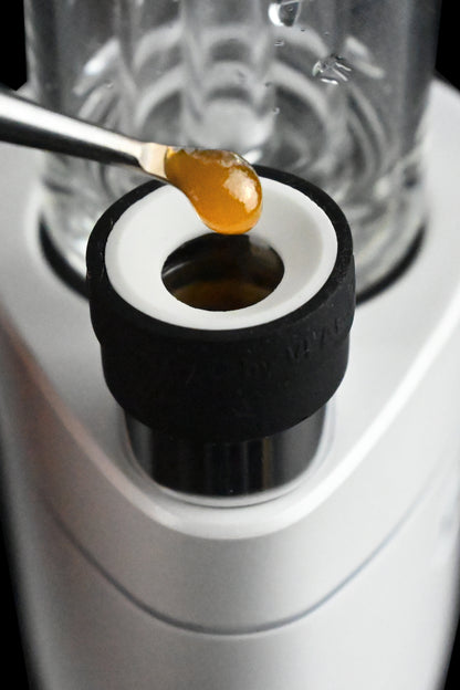 Cannabis concentrate, or "dab," on a metal tool hovering over the bowl of a vaporizer.