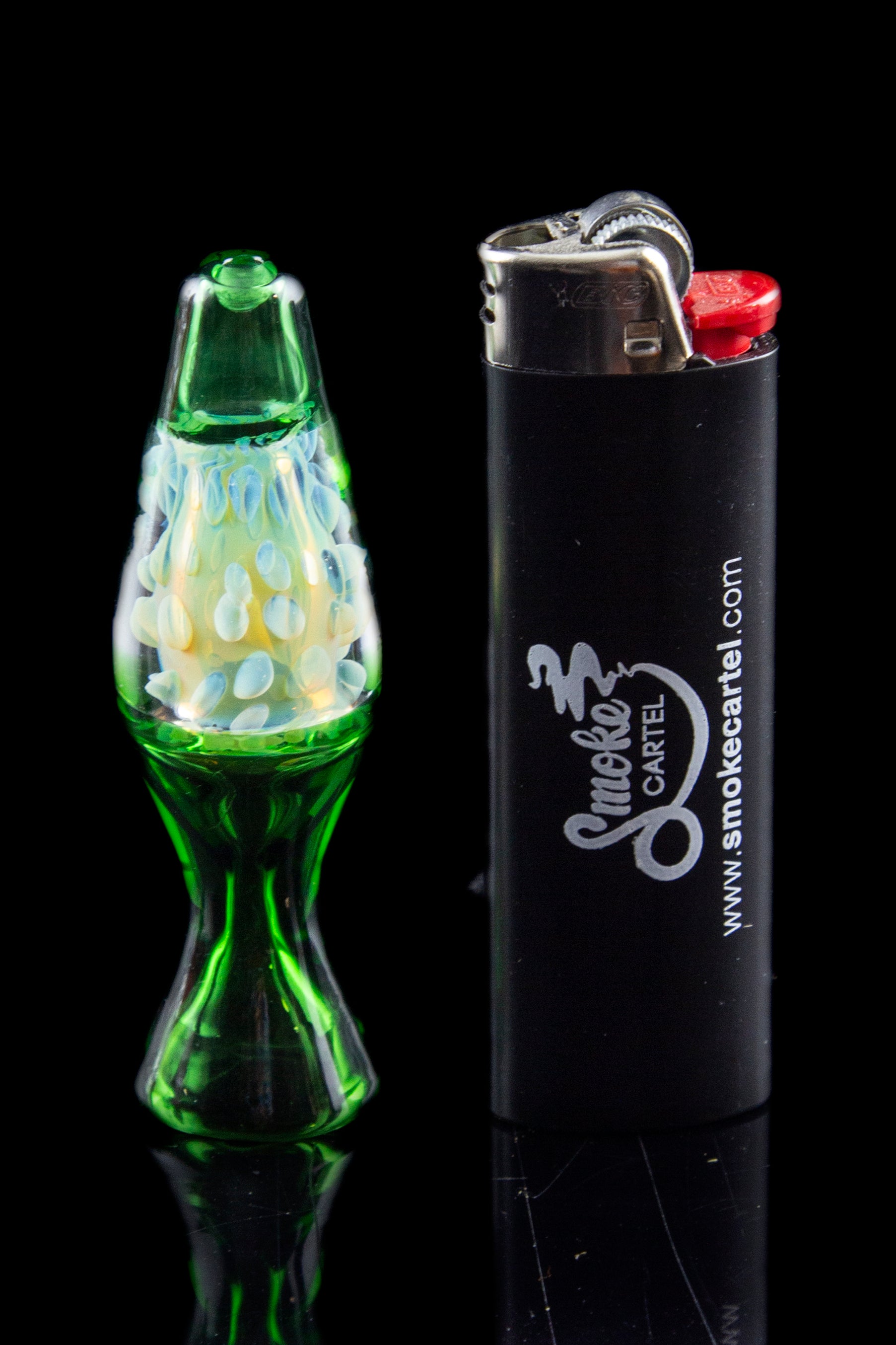 Green glass cannabis oil burner pipe with colorful swirls next to a black lighter branded with “Smoke Cartel.”