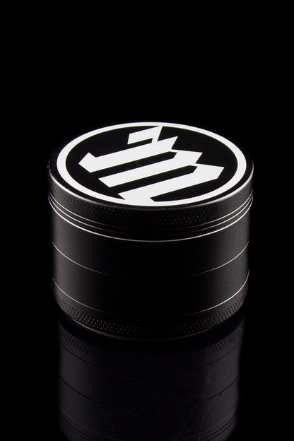 Black metal cannabis grinder with a white logo on top.