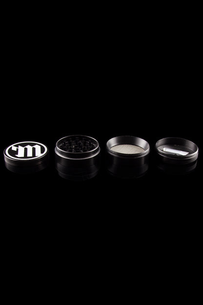 Silver cannabis grinder disassembled into its component parts on a black background.