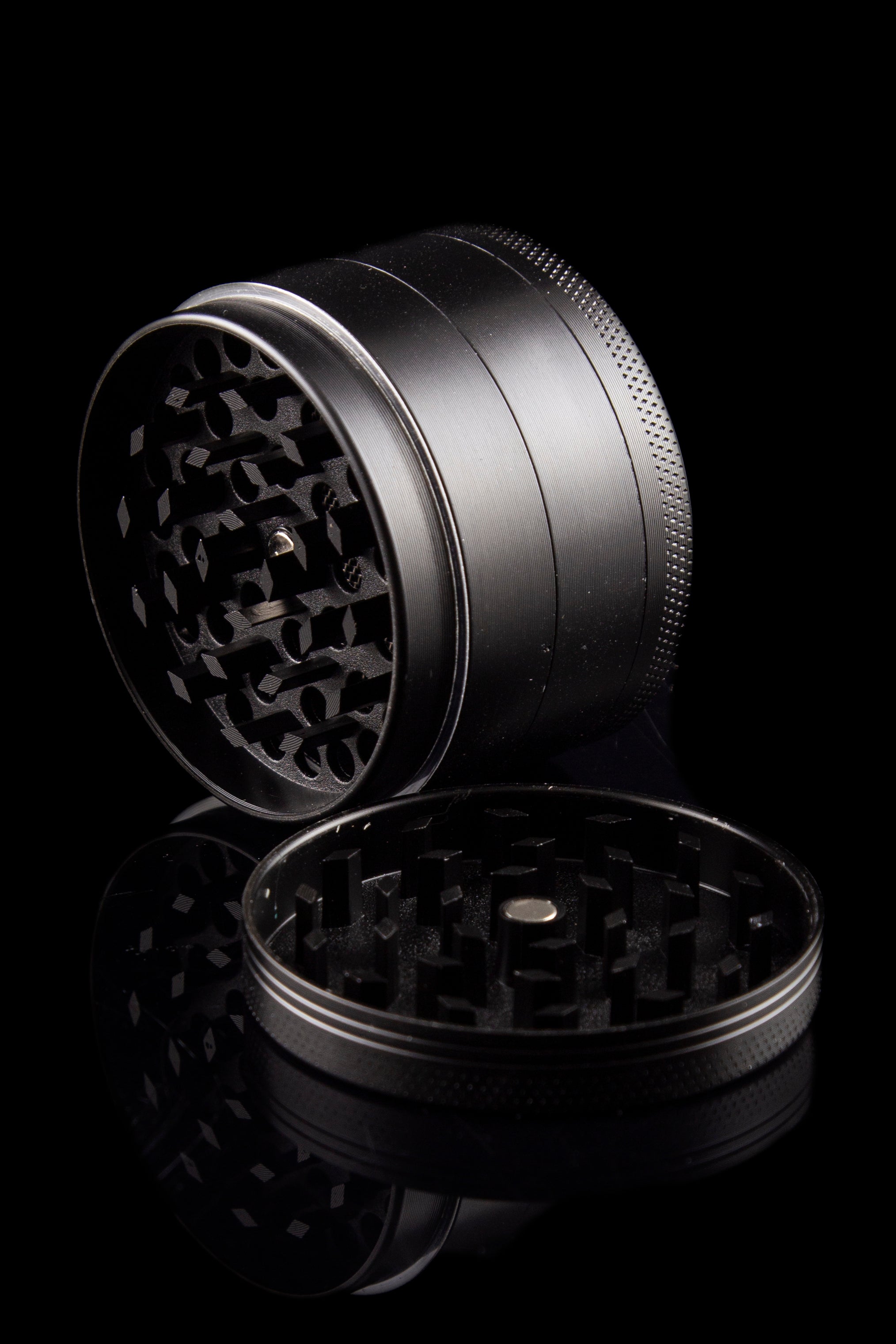 Black metal cannabis grinder, open with visible grinding teeth.