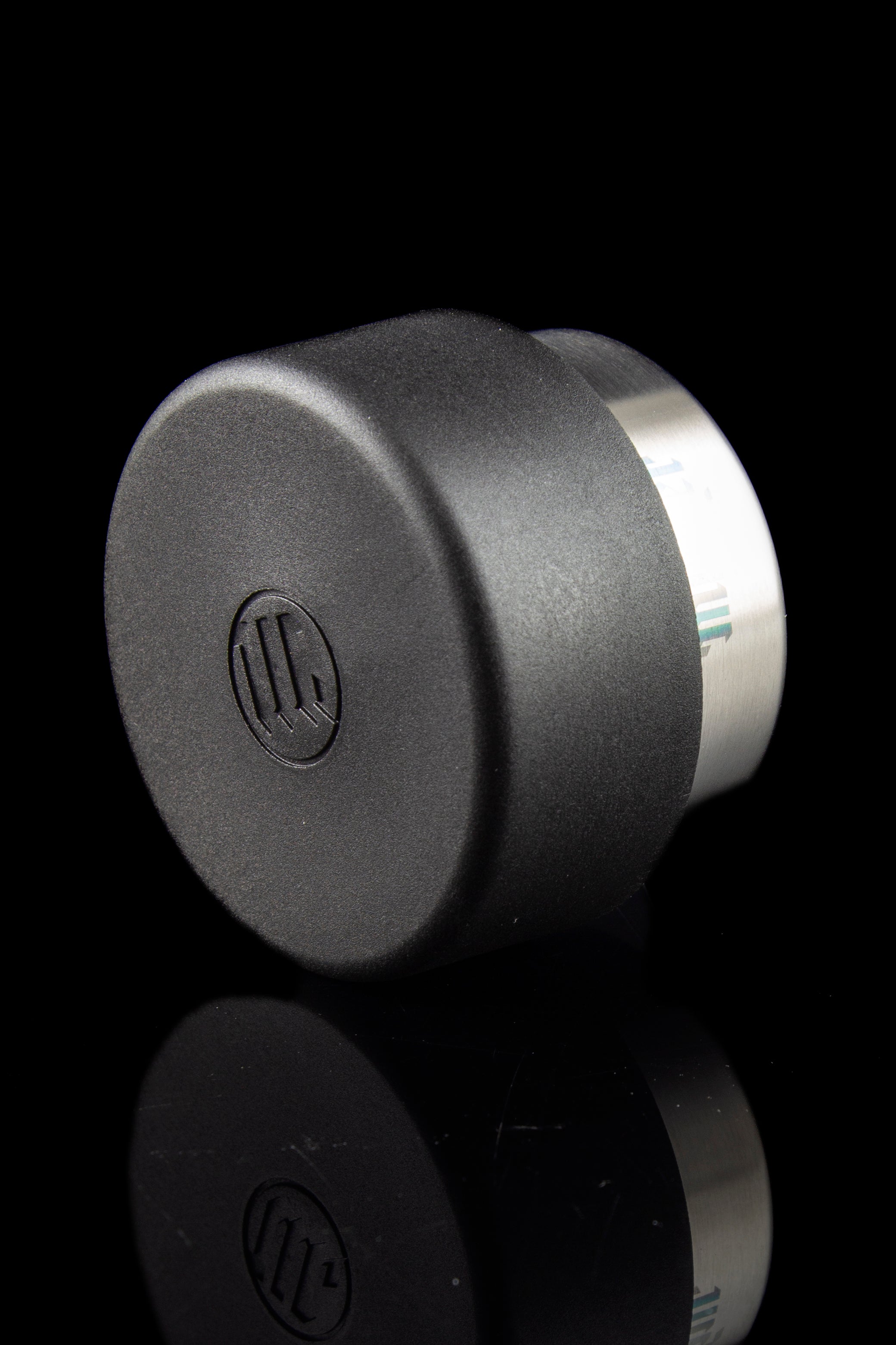 Black cannabis oil concentrate container with reflective surface, featuring a branded logo.