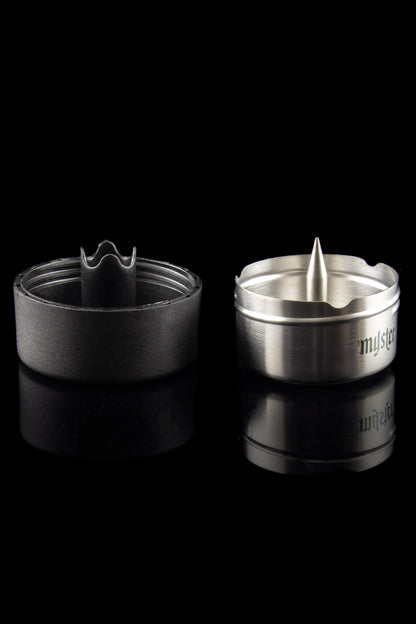 Silver cannabis smoking bowl with a spiked interior and removable screen, reflected on a dark surface.