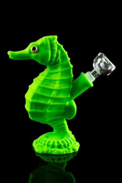 A front view of the Premium Silicone Seahorse Molded Water Pipe, showcasing its green, sculpted form against a dark reflective surface.