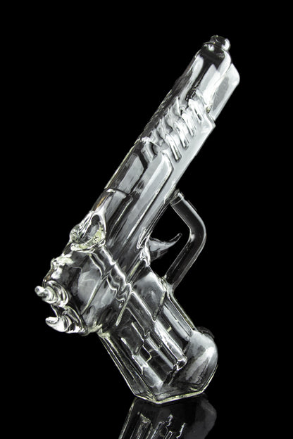 Clear glass pipe shaped like a handgun, reflecting on a black surface.