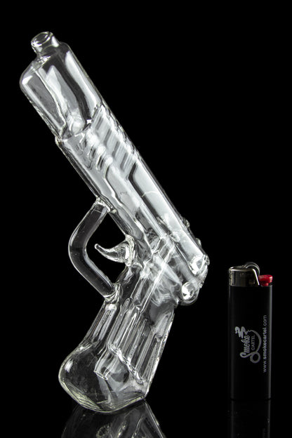 Clear glass pipe shaped like a handgun, displayed with a lighter.