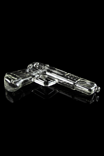 Glass pistol-shaped cannabis pipe on a reflective black surface.