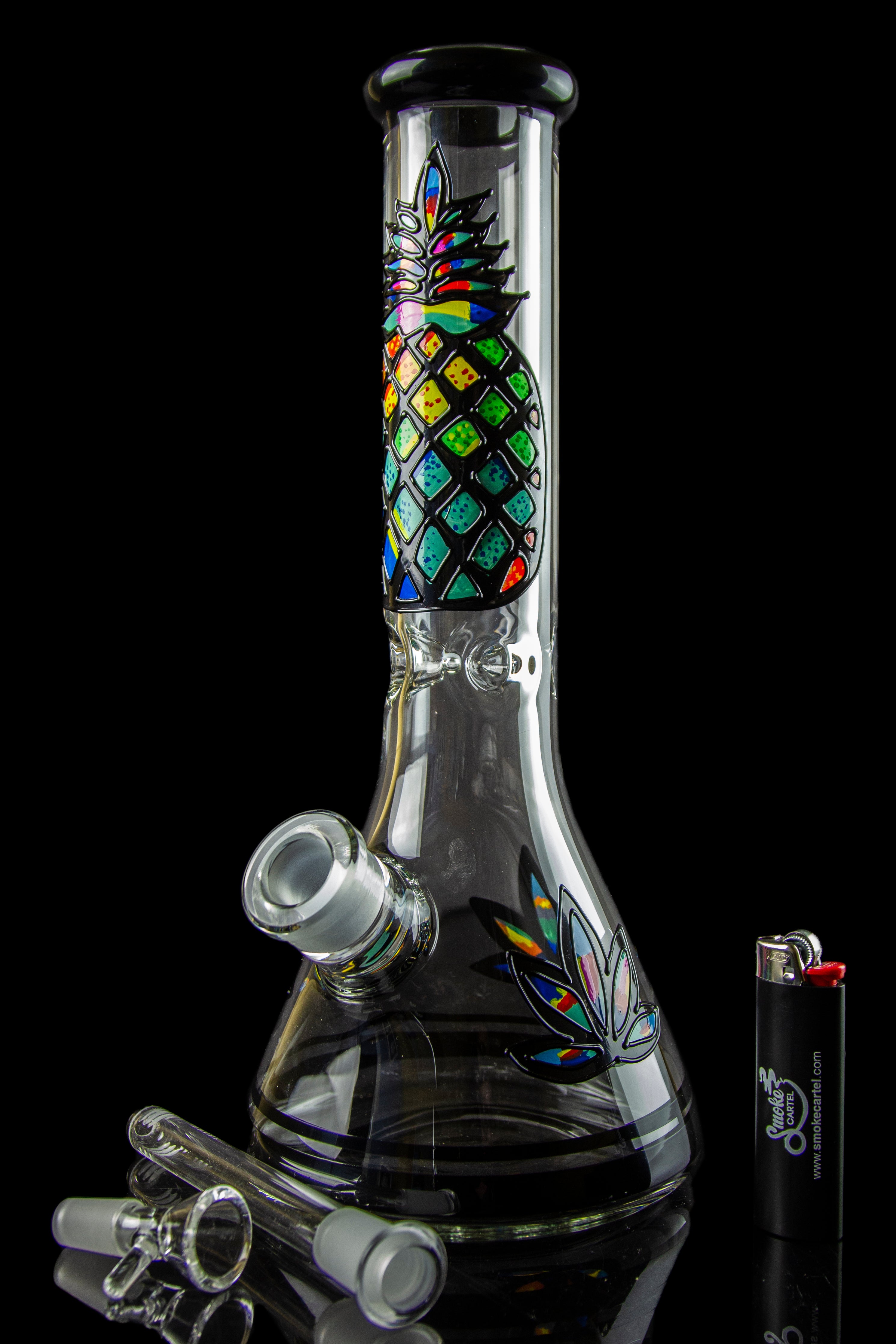 A colorful glass bong with a patterned design, accompanied by glass smoking accessories on a dark background.