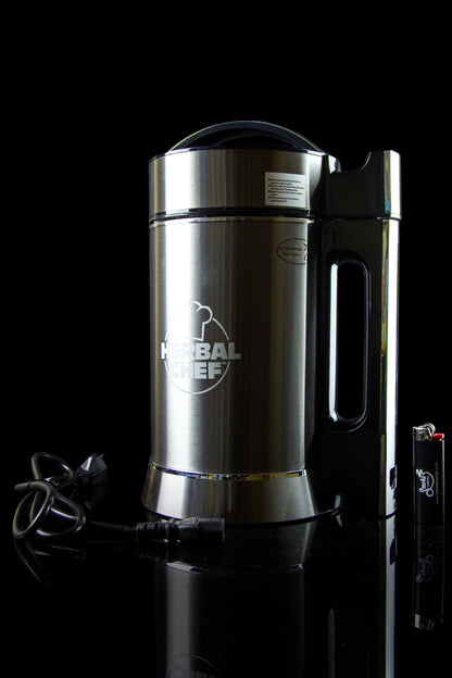 Stainless steel Herbal Chef infusion appliance with power cord and lighter on a reflective black surface.