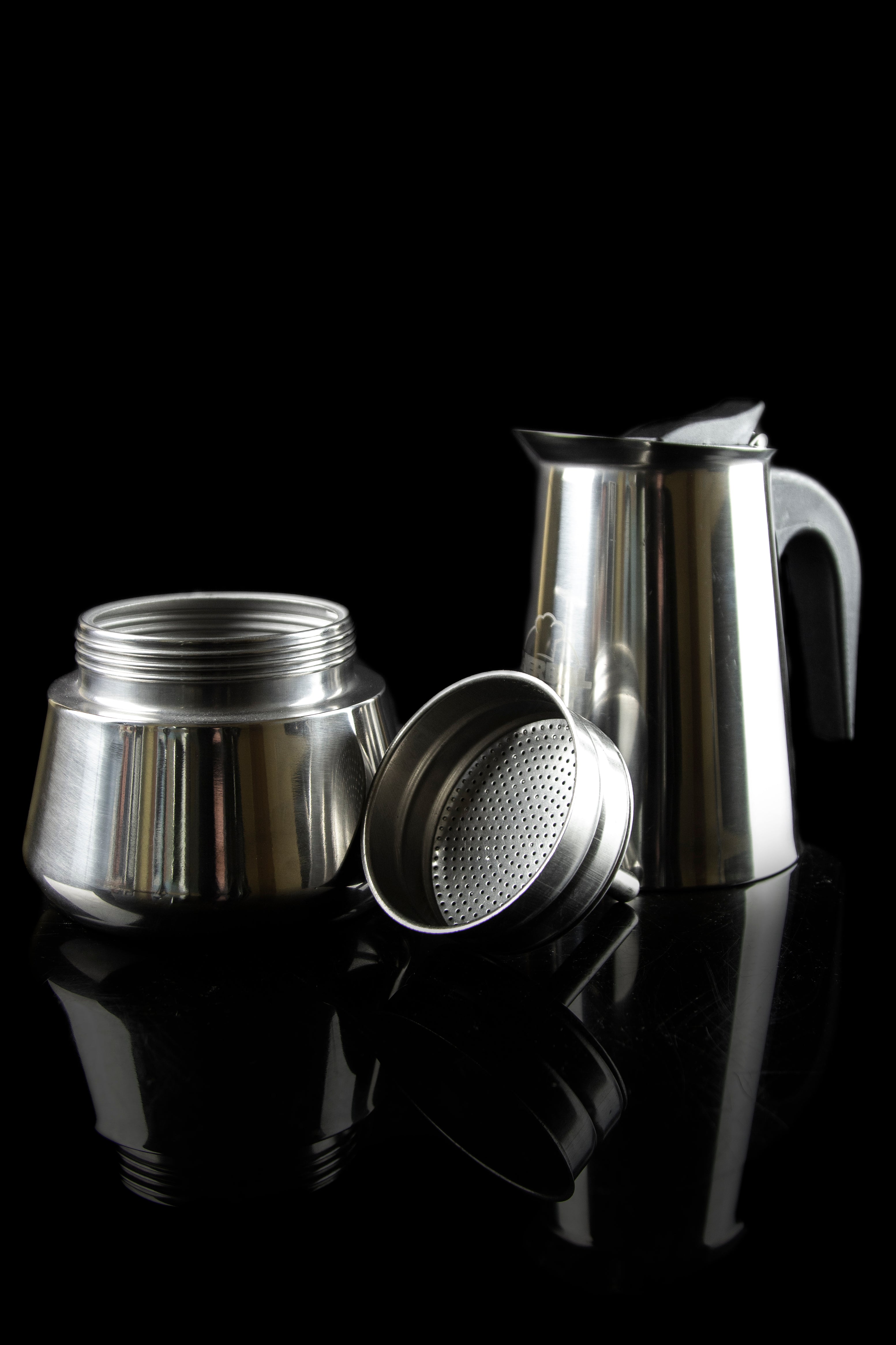 Silver cannabis percolator disassembled on a reflective black surface.