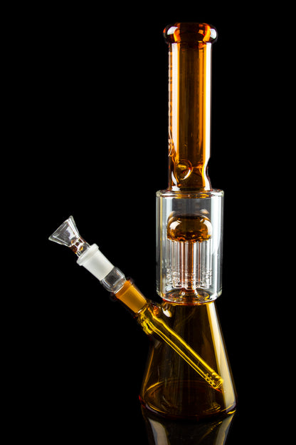 Amber glass water pipe (bong) with intricate percolator and detachable bowl, isolated on black.