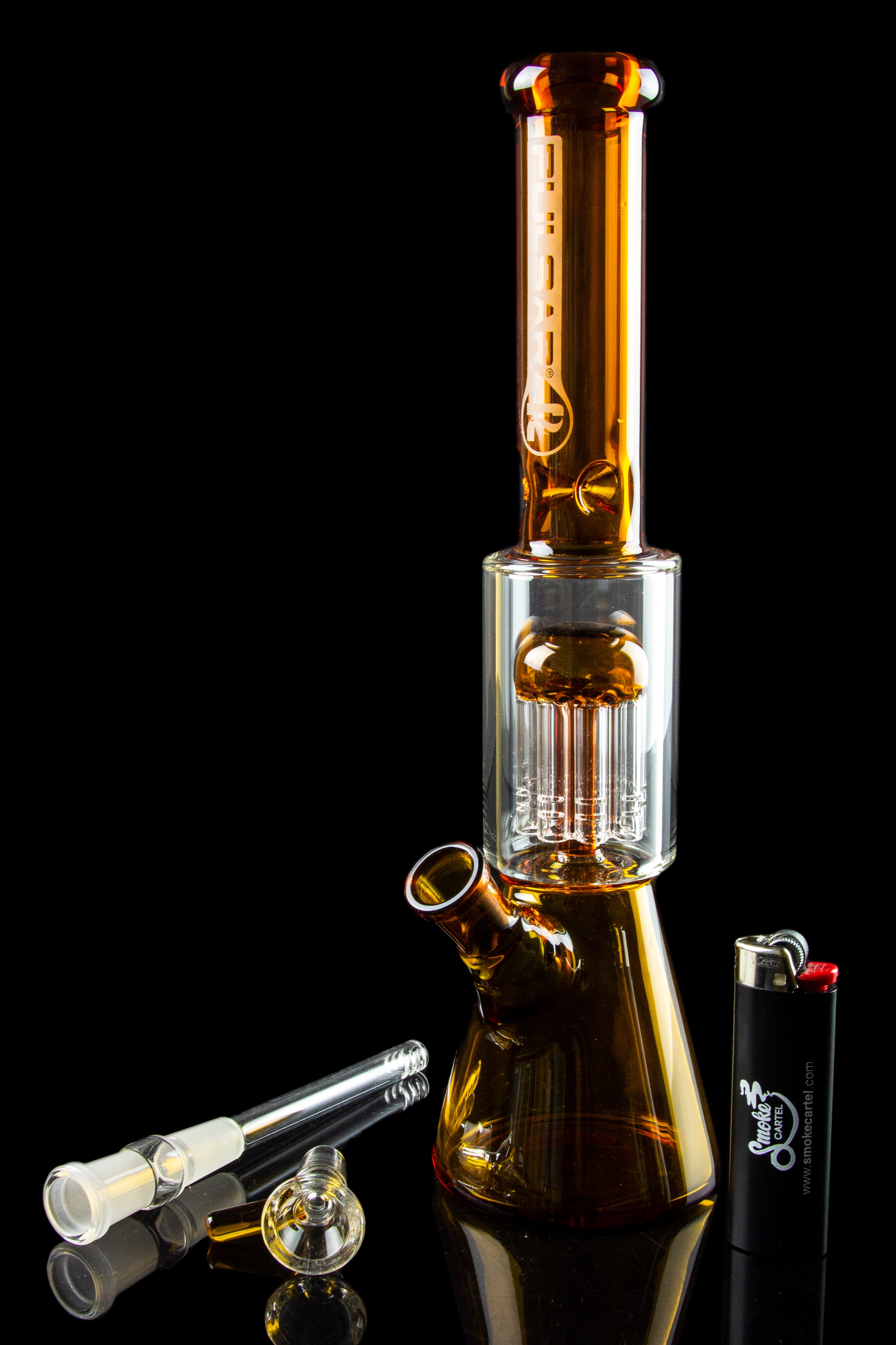 Glass water pipe (bong) with detached glass pieces and lighter against a black reflective surface.