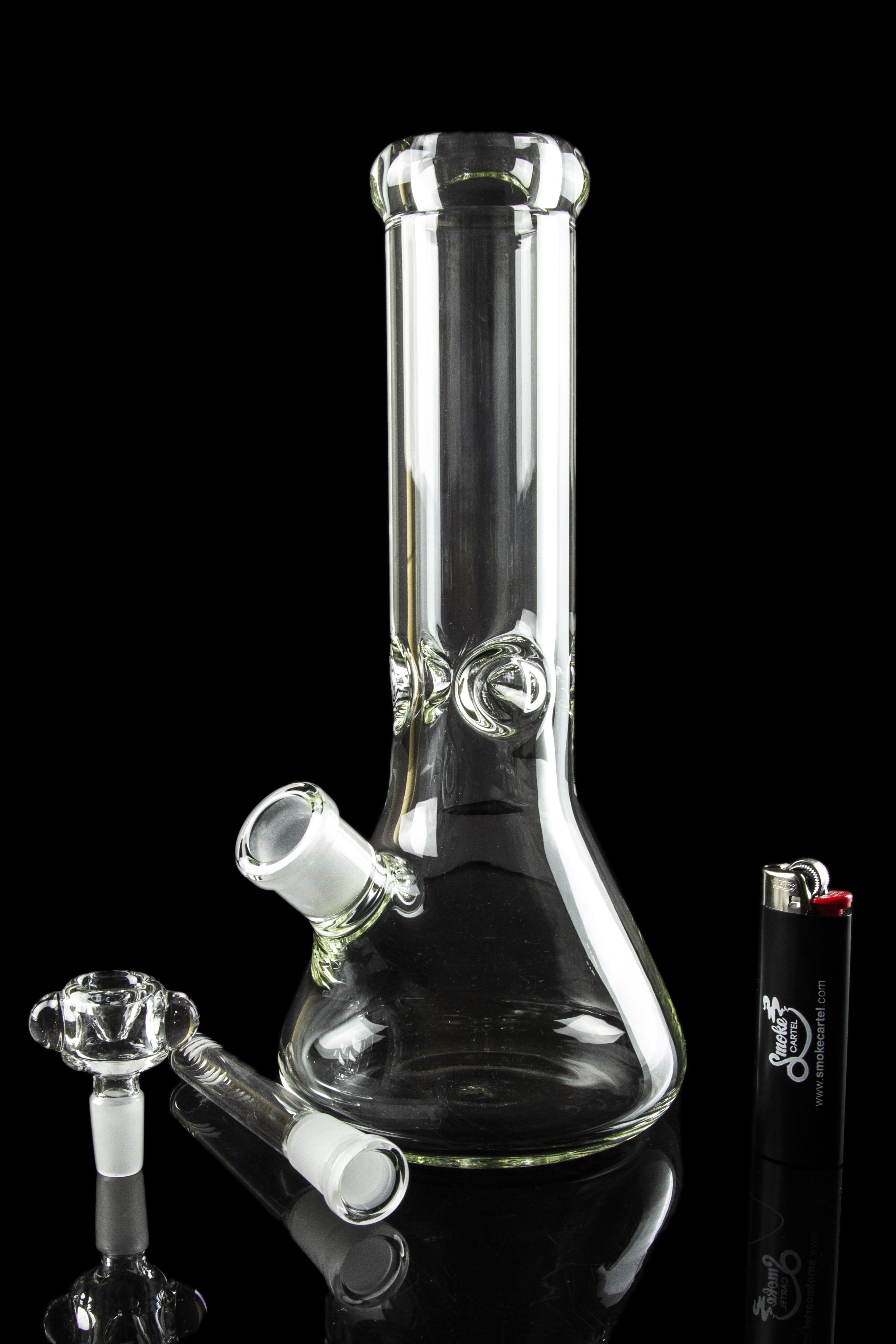 Glass bong with removable downstem and bowl, positioned next to a lighter on a reflective black surface.